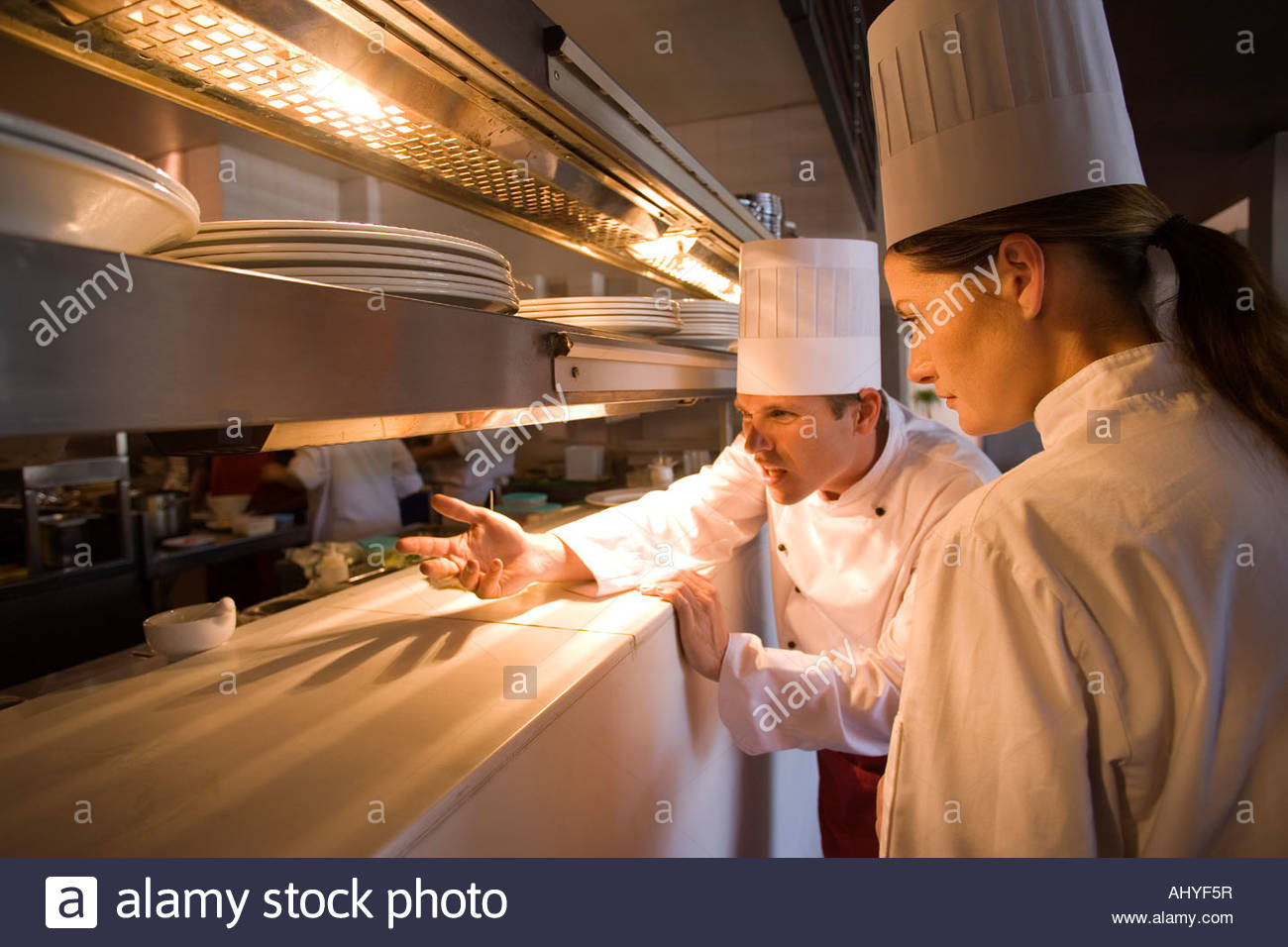 Male and female chefs standing at order counter in commercial kitchen