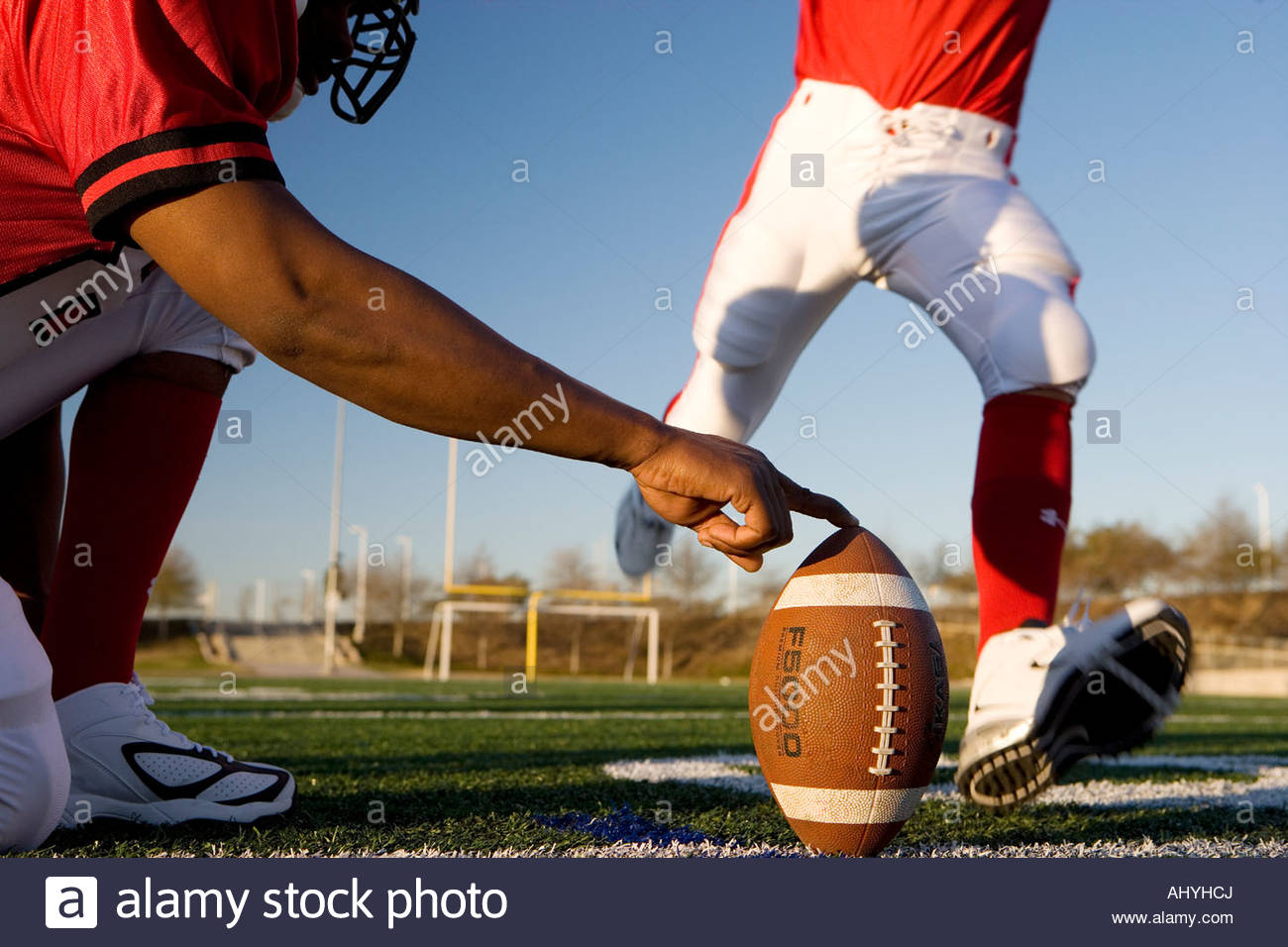 American football player attempting to kick field goal, teammate Stock