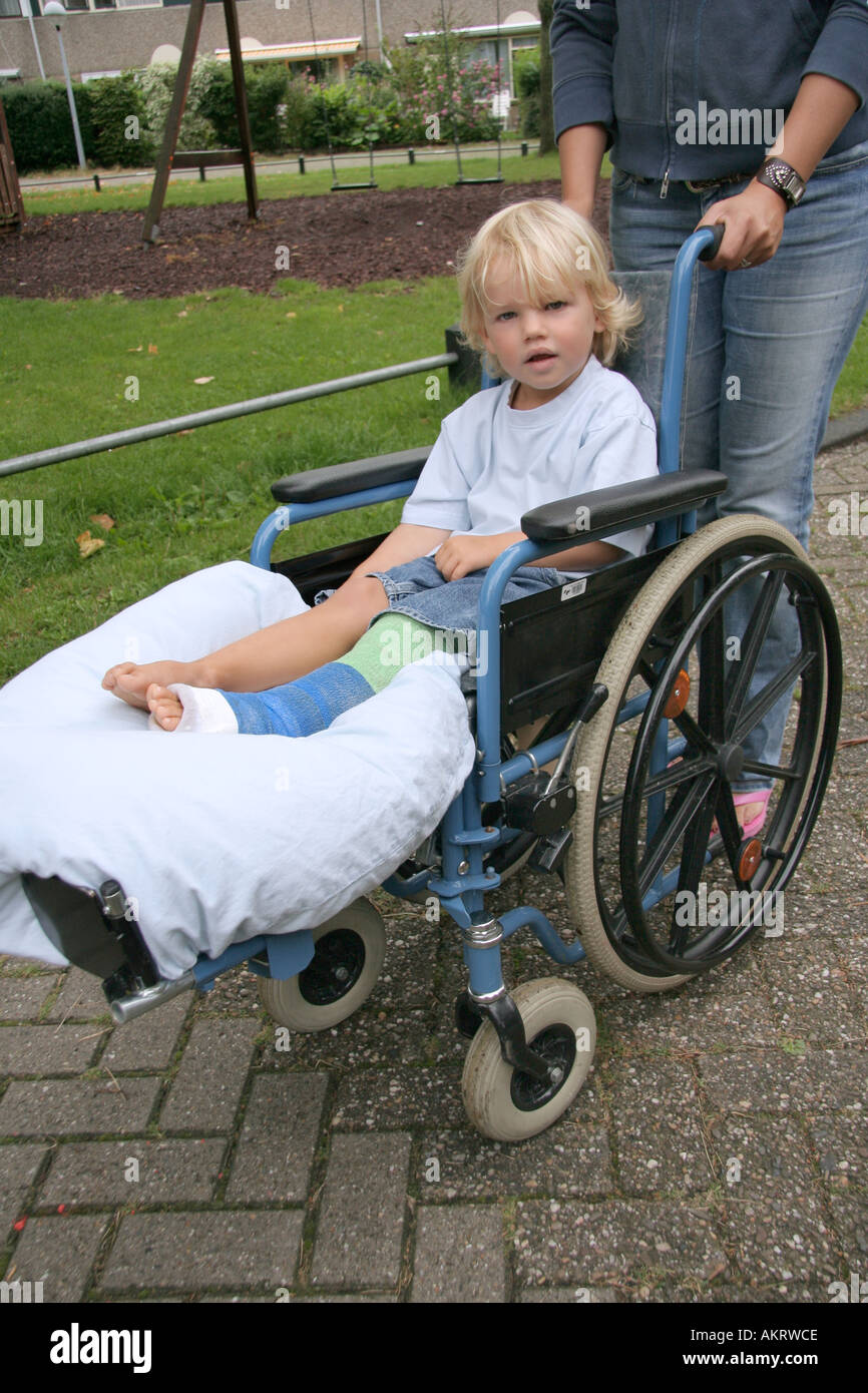 Little boy with a broken leg sitting in a wheelchair Stock Photo