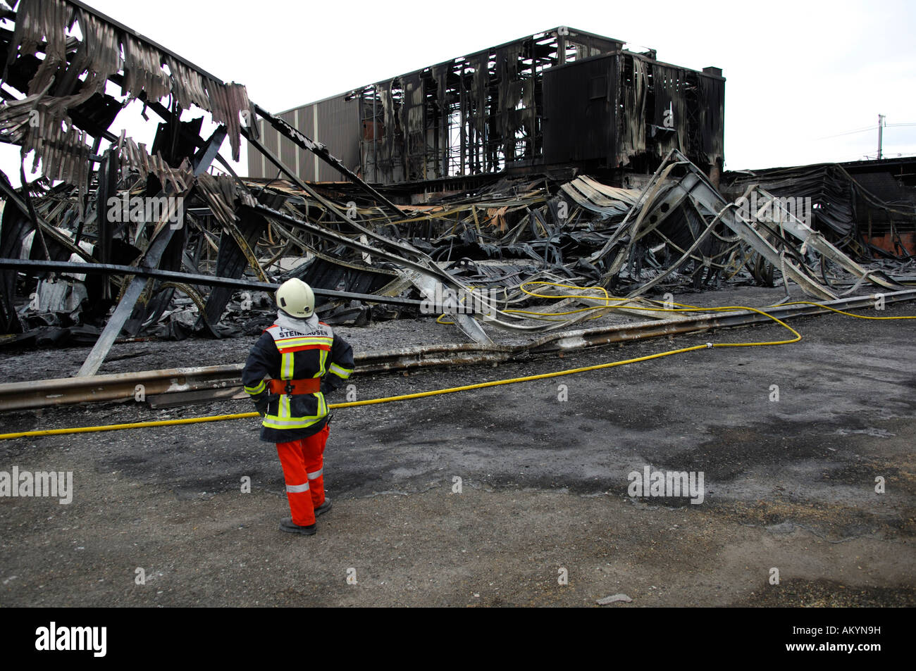 fireman-in-front-of-a-burnt-down-factory-building-swisspor-steinhausen-AKYN9H.jpg