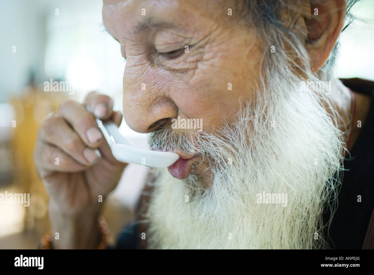 elderly-man-with-long-beard-eating-with-chinese-soup-spoon-ANFEJG.jpg