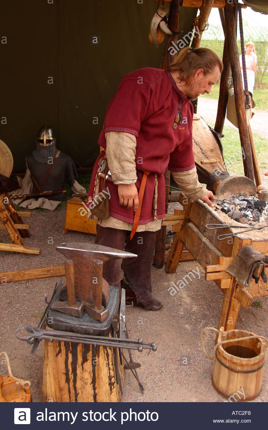 A blacksmith dressed up in medieval viking era clothes works in his