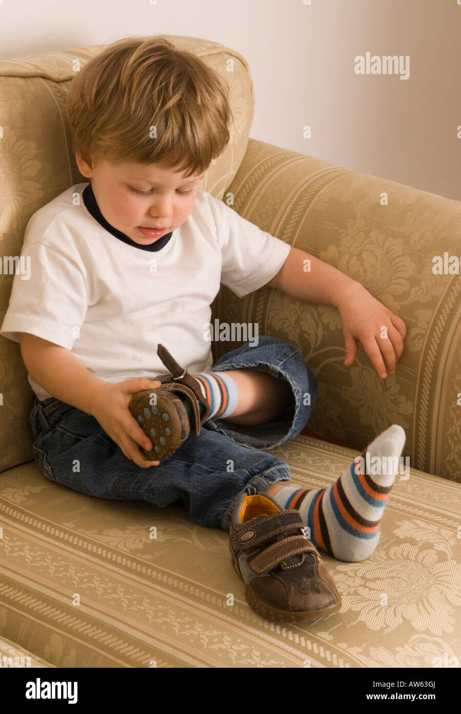two year old boy trying to put his shoes on Stock Photo, Royalty Free