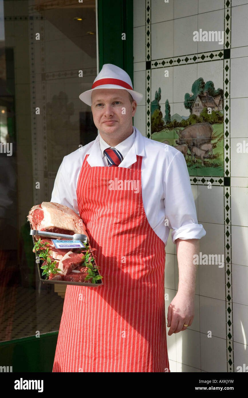 Butchers in Shop Doorway wearing Red Apron W Irvine Butchers Stock