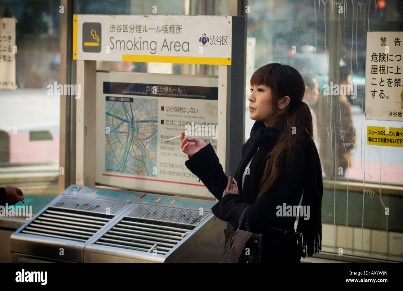 Japanese woman smoking a cigarette at a Tokyo bus shelter Stock Photo