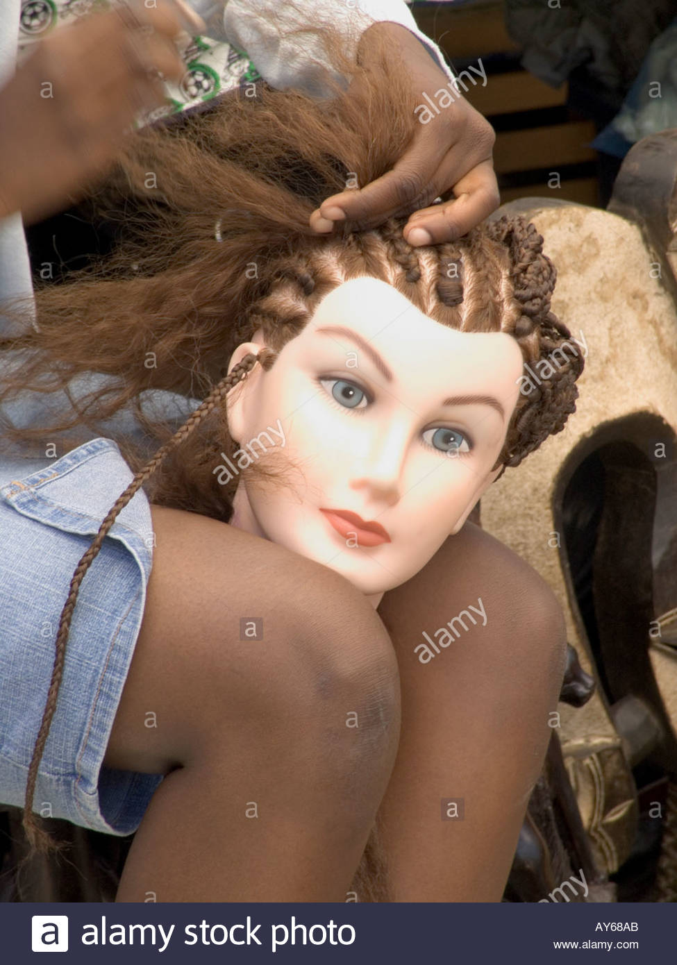girl practicing braiding hair on a mannequins head Stock Photo, Royalty