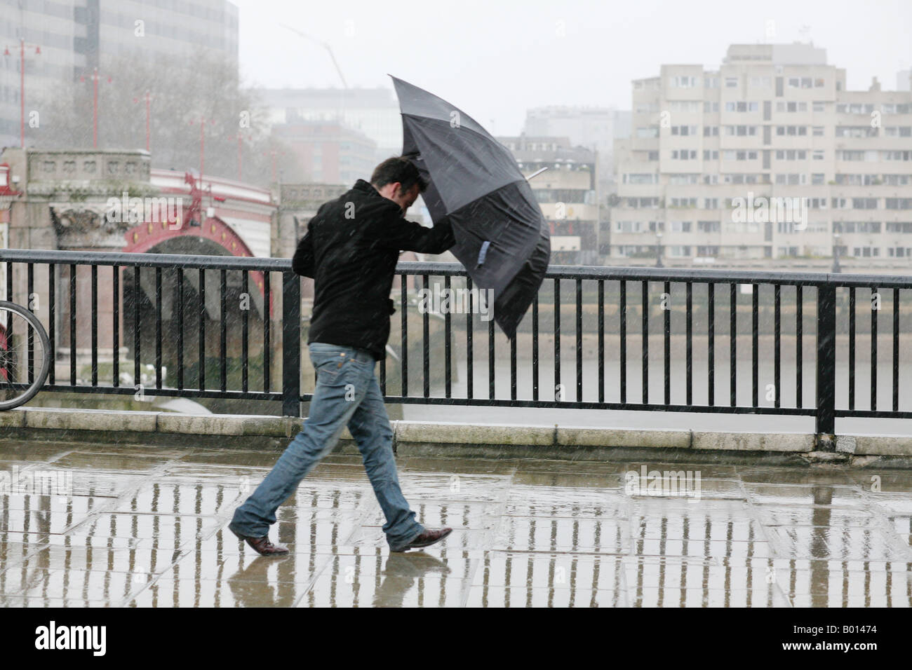 Man with umbrella brolly in a heavy rain downpour in London UK Stock