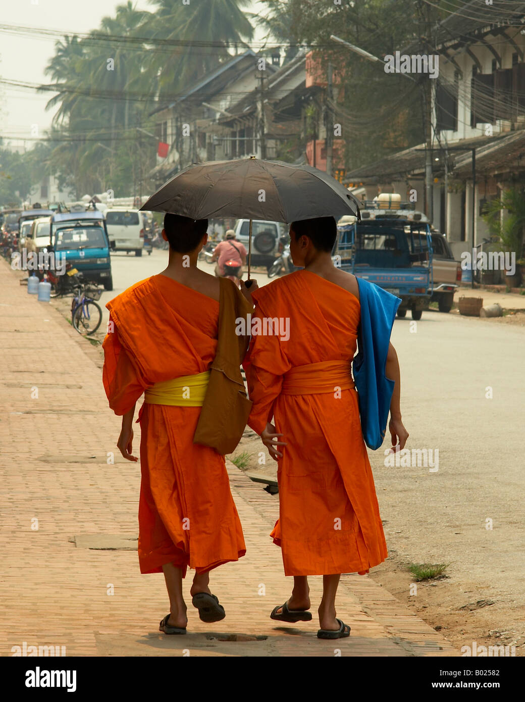 Two Buddhist Monks Walking With An Umbrella Through The Main Road In