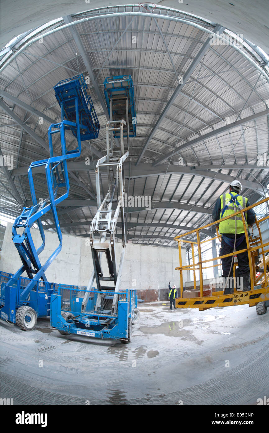Two scissor lift platforms extended for working on steel roof with