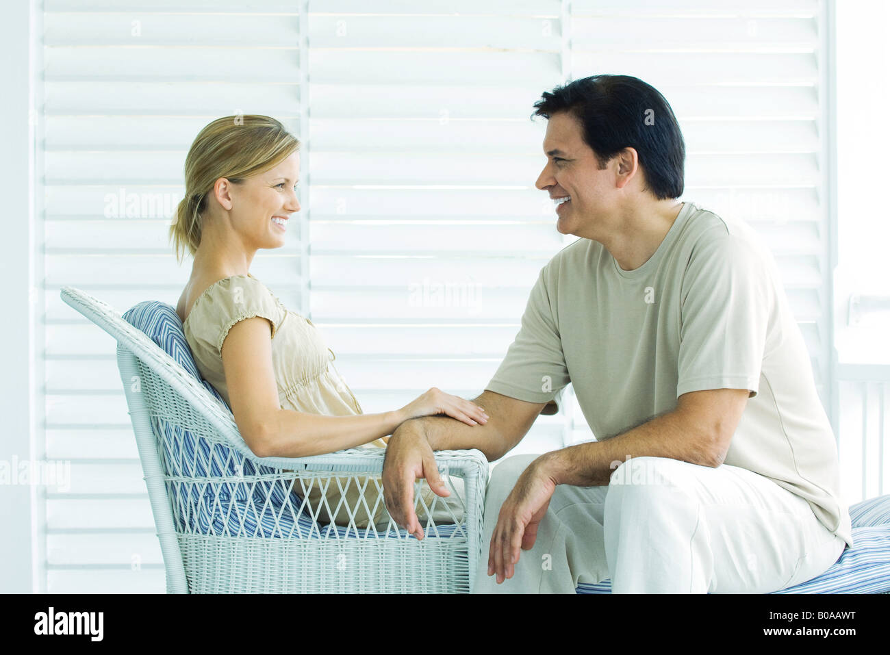 Couple sitting face to face on porch, smiling, woman Couple sitting face to face on porch, smiling, woman