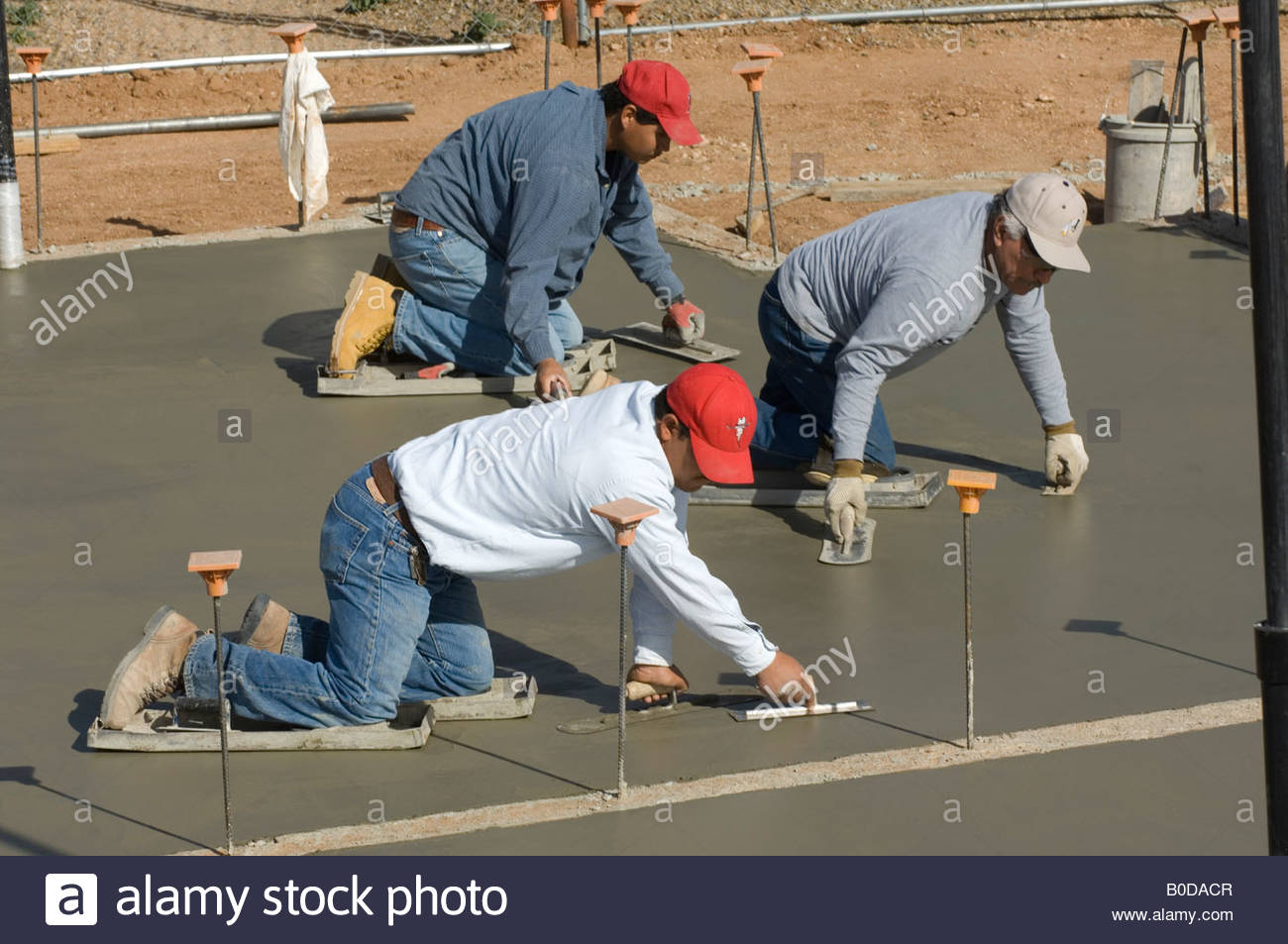Wet cement that is almost completely dry with three workers putting