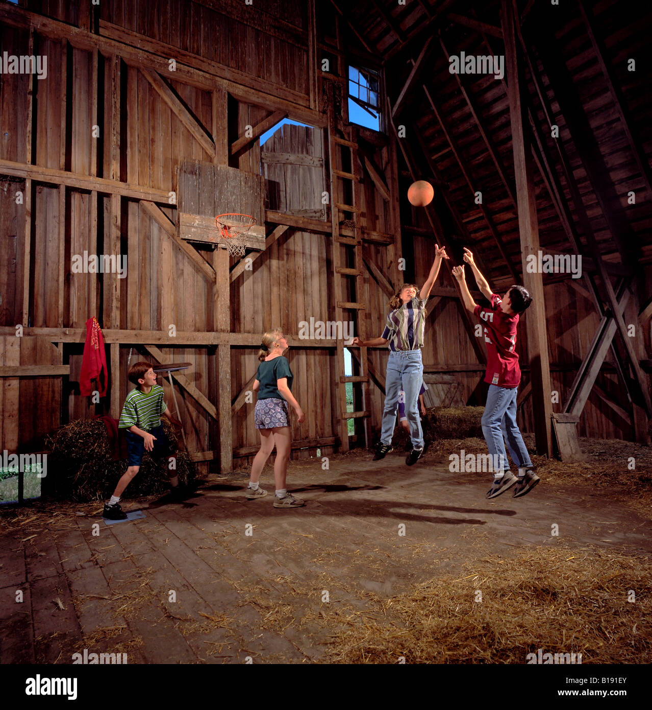 Four youth play basketball inside a barn loft Stock Photo, Royalty Free