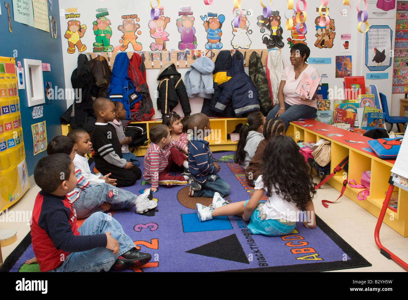 African American preschool teacher reading a book to her class Stock
