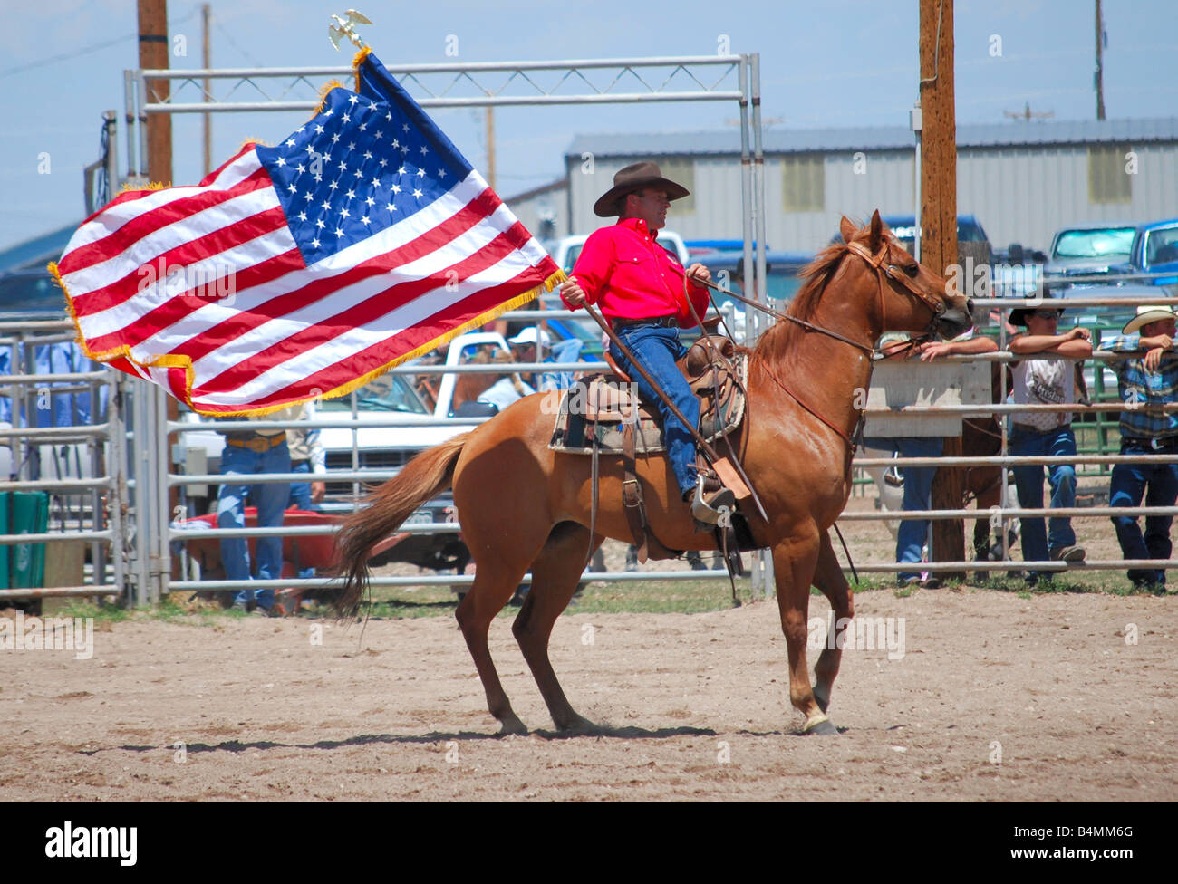 Cowboy carrying an American flag while riding on a horse at a rodeo