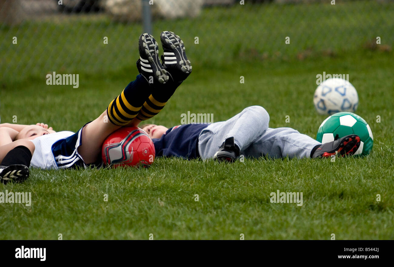 Young kids laying on the ground after a tiring soccer practice Stock