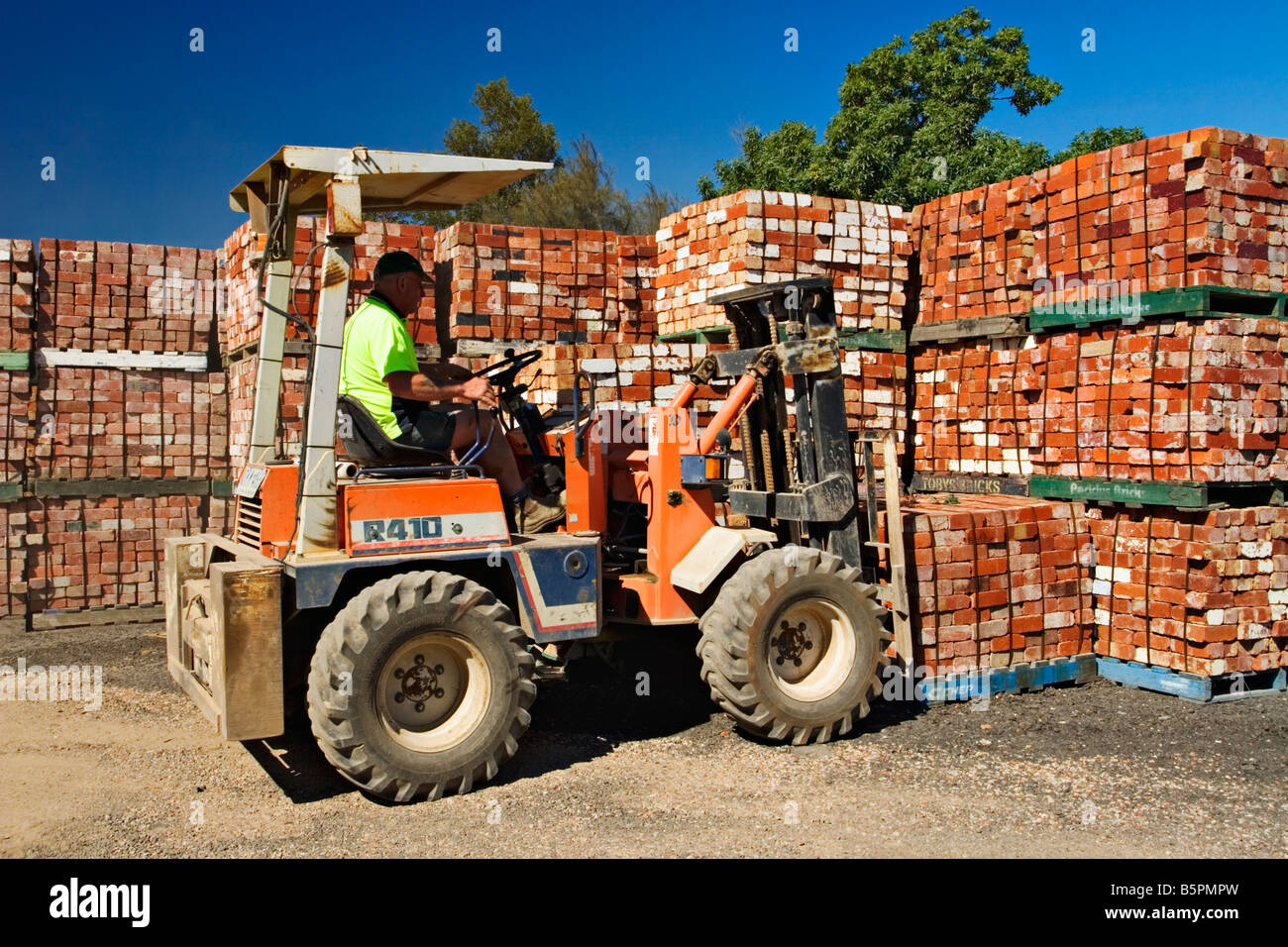 Building Materials / A Forklift Driver stacks used Bricks in a Stock