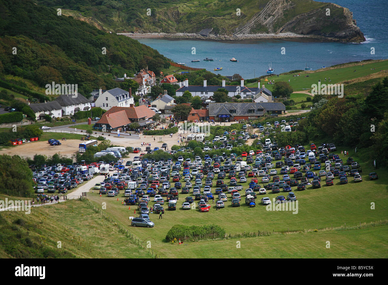A busy car park and the South West Coastal Footpath at Lulworth Cove