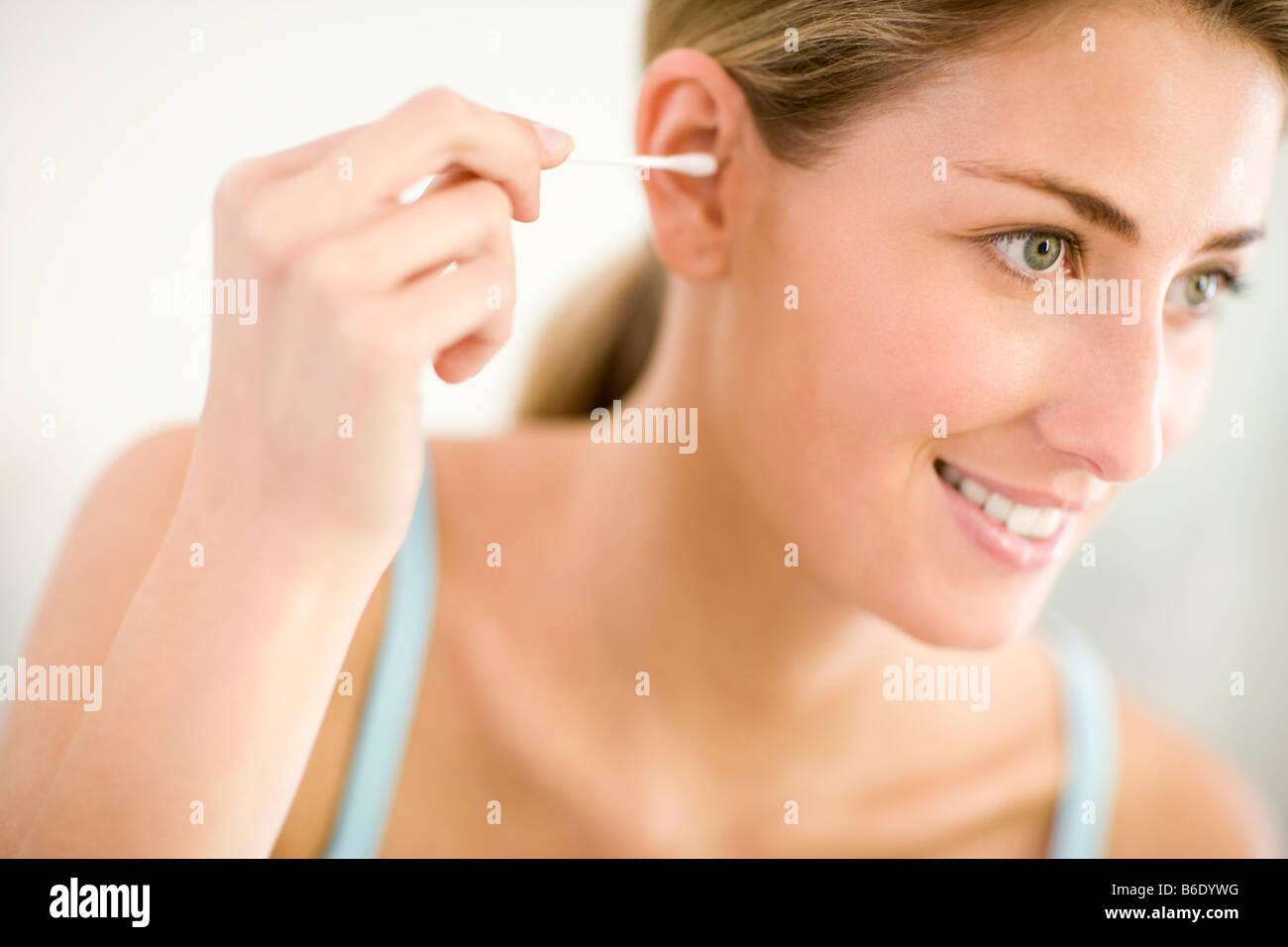 Cleaning ears. Woman using a cotton bud to clean her ear. Cotton buds