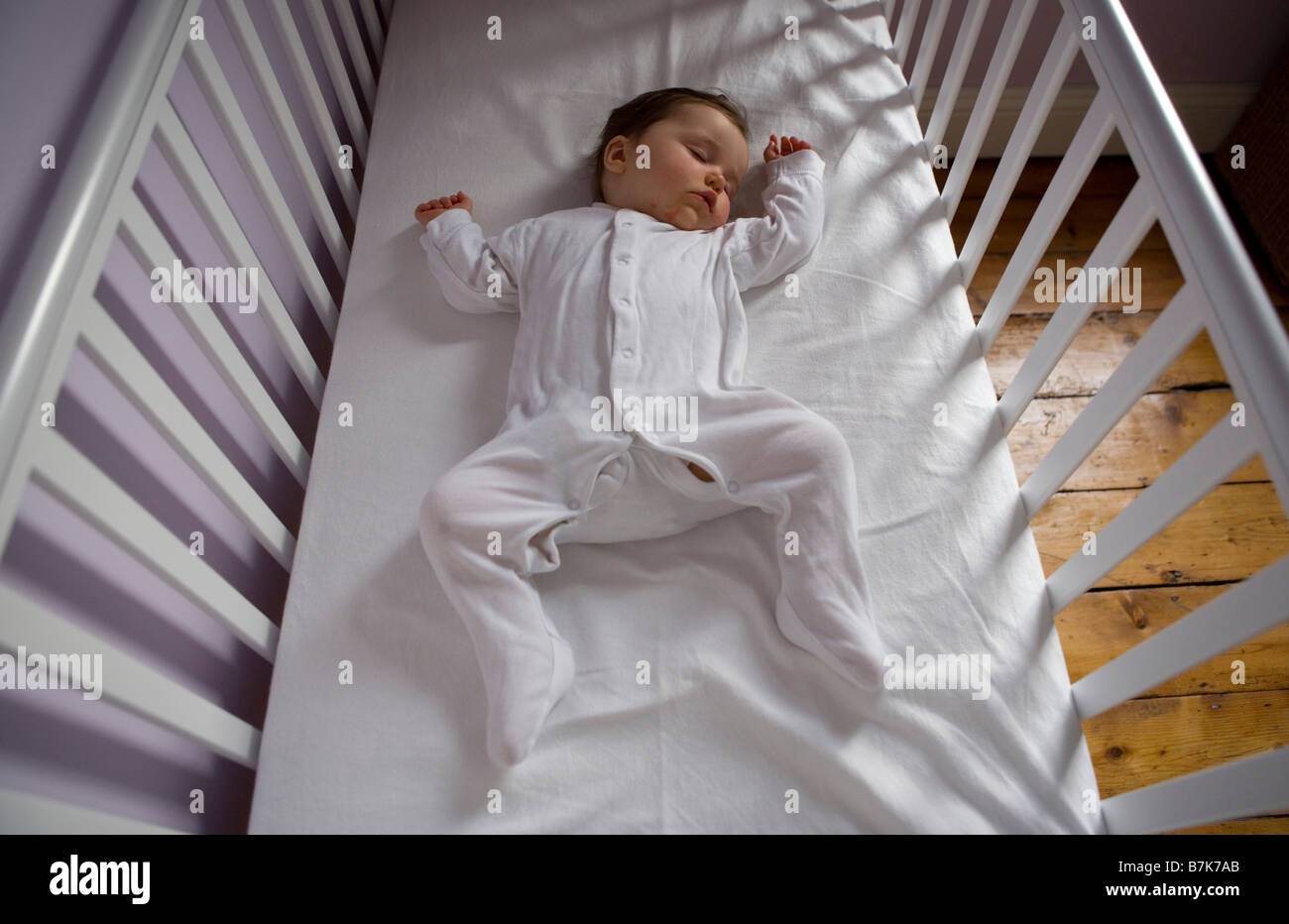 A baby girl lies sleeping in her cot Stock Photo, Royalty Free Image