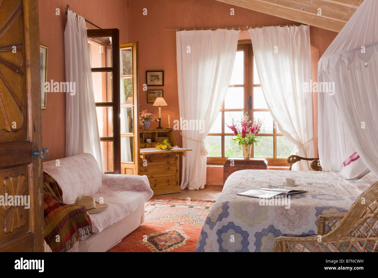White Mosquito Net Above Bed With Patchwork Quilt In Terracotta