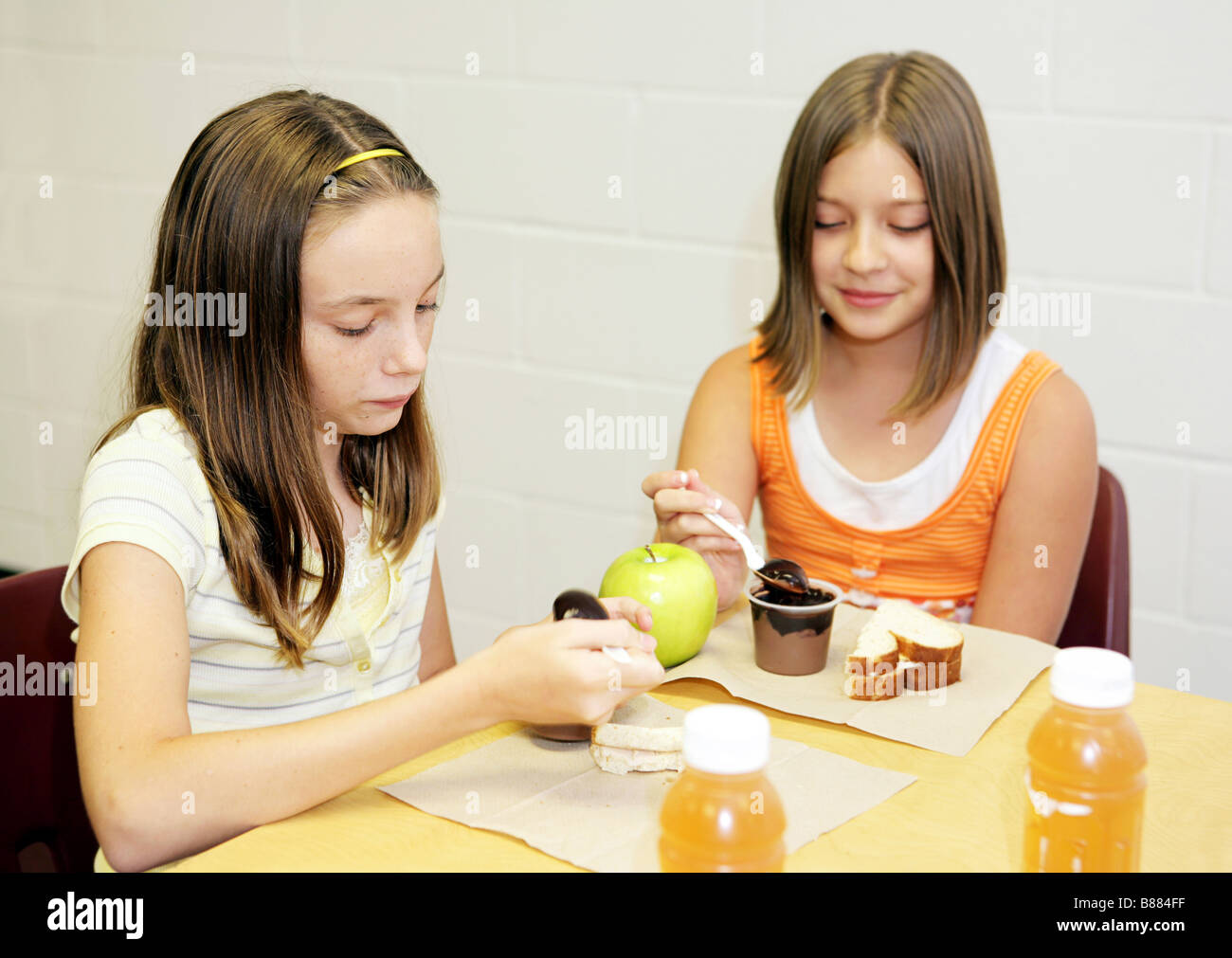 Two school girls eating lunch together in the cafeteria Stock Photo