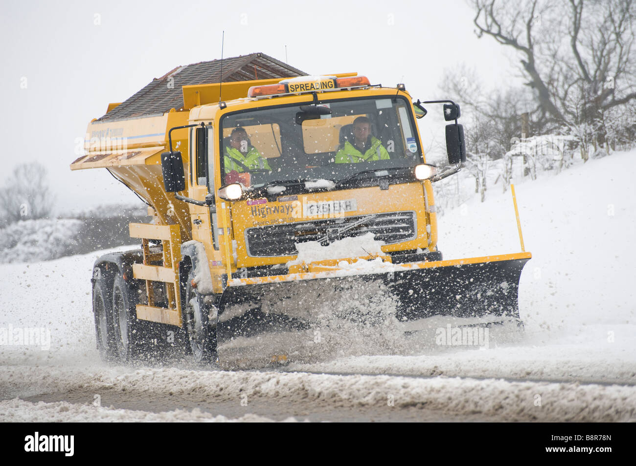 Gritter lorry with snow plough fitted to the front clearing the roads