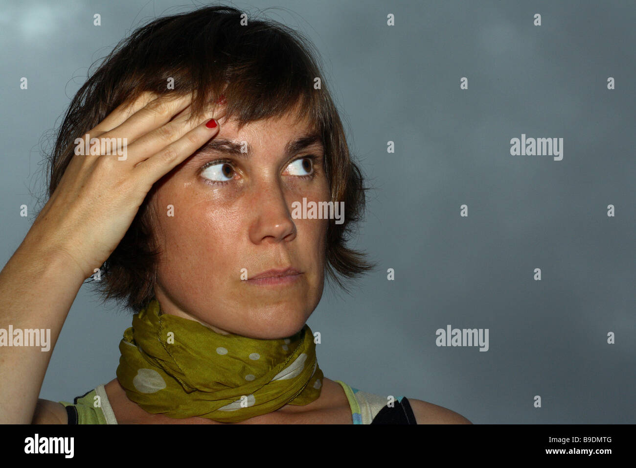 Stock Photo - Woman with headache in front of a dark rainy sky - woman-with-headache-in-front-of-a-dark-rainy-sky-B9DMTG