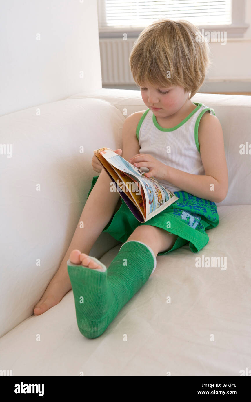 Little boy with a broken leg reading a comic book Stock Photo, Royalty
