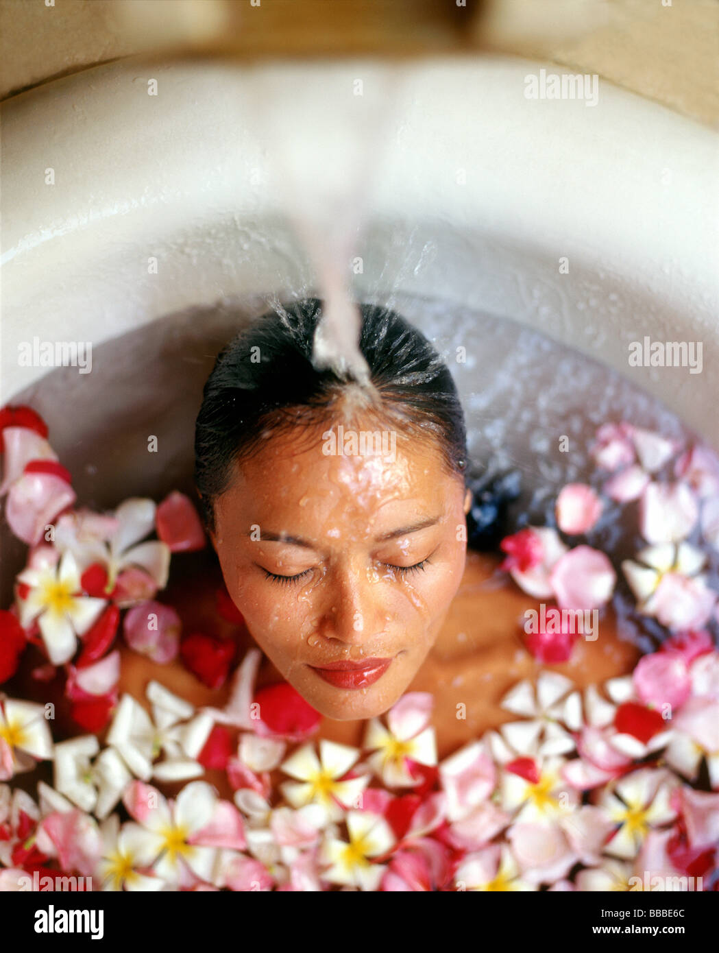 Stock Photo - Woman in bath with floating flowers, head under <b>running water</b> - woman-in-bath-with-floating-flowers-head-under-running-water-BBBE6C