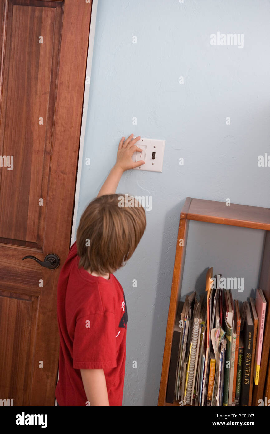 Seven year old boy turning off and on light switch in his bedroom