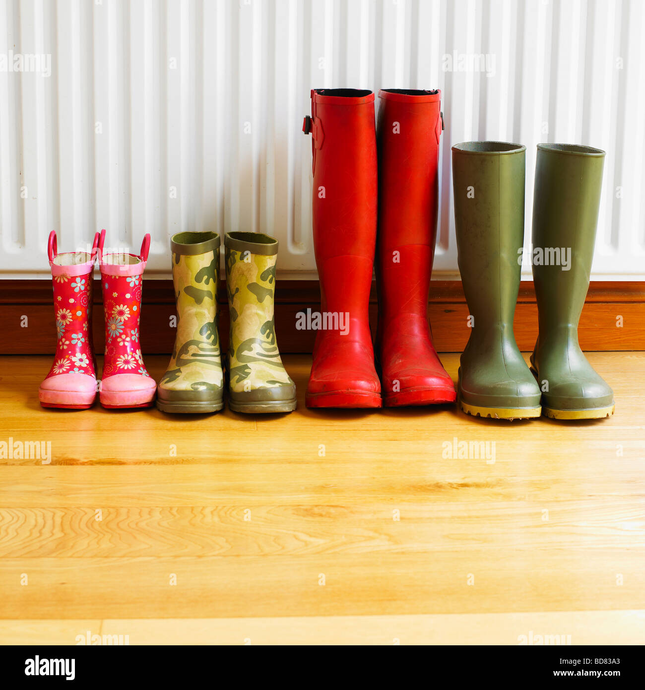 A family's Wellington Boots line up drying in front of a radiator Stock Photo, Royalty Free