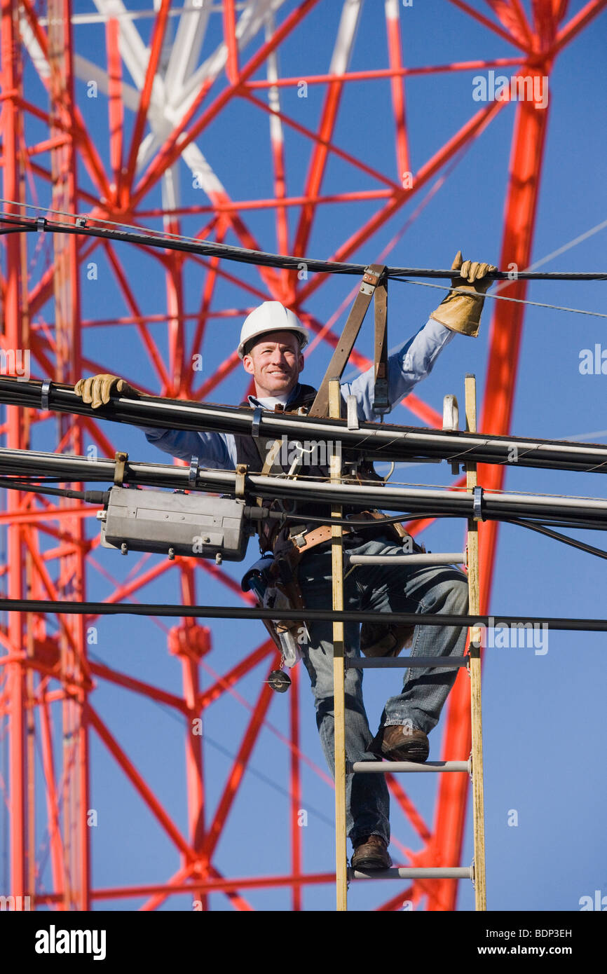 Cable lineman climbing a ladder to repair transmission line Stock Photo