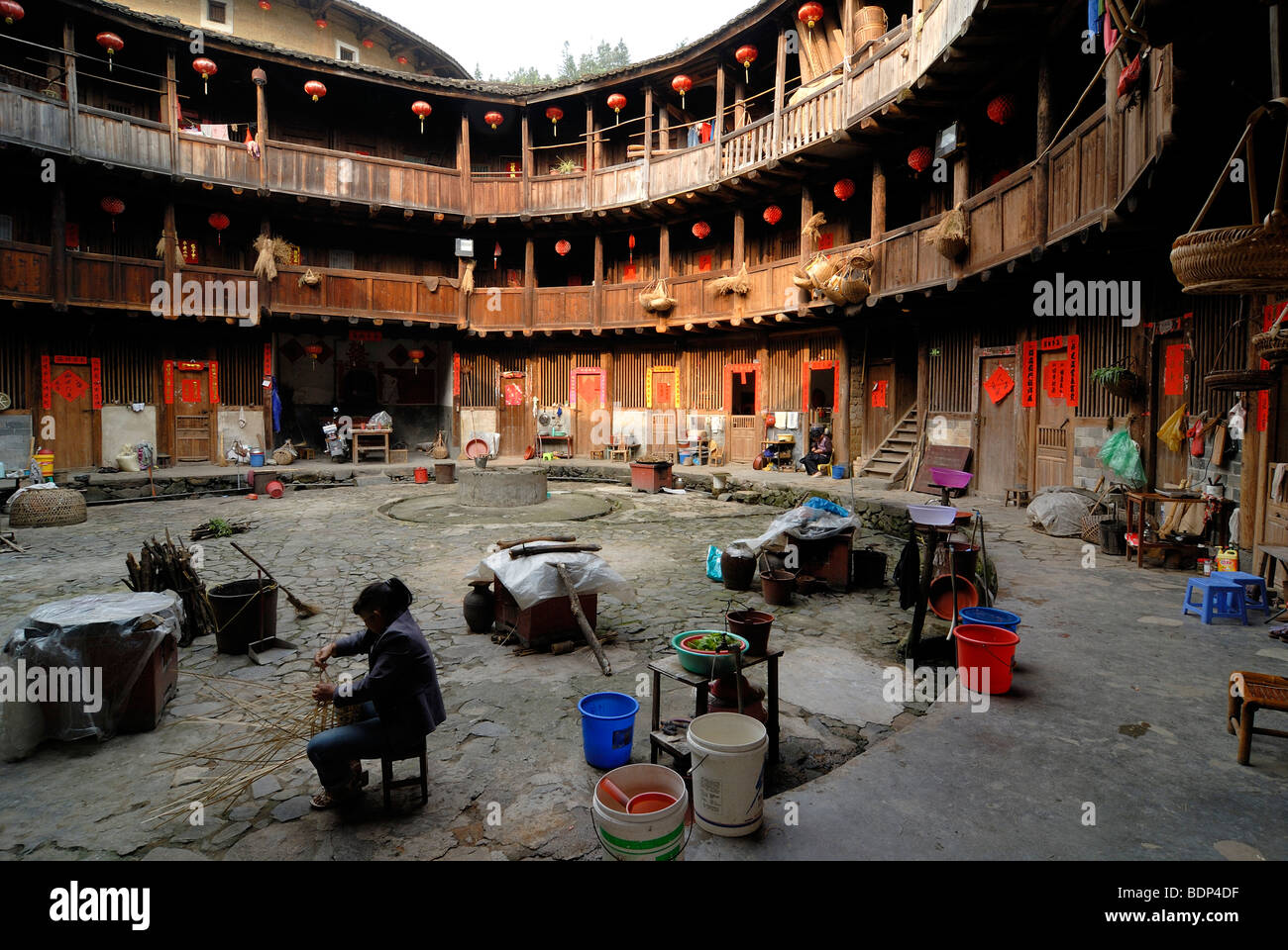 Chinese basket weaver sitting in the courtyard of a round house Stock