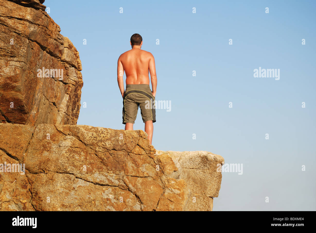 Man Standing On Cliff Edge Looking Out To Sea Man Standing On Cliff Edge Looking Out To Sea