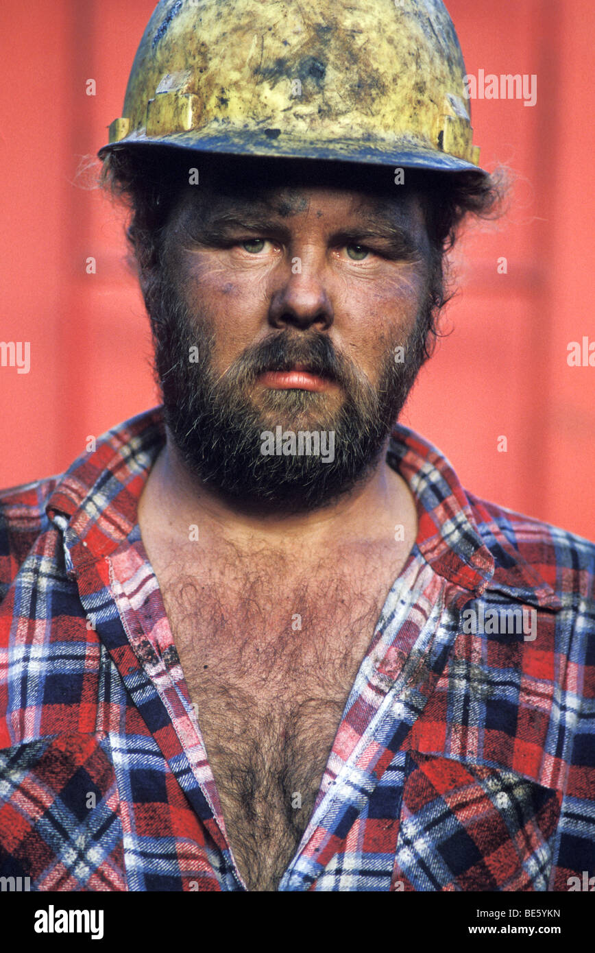 Dirty, serious, bearded construction worker in hardhat Stock Photo