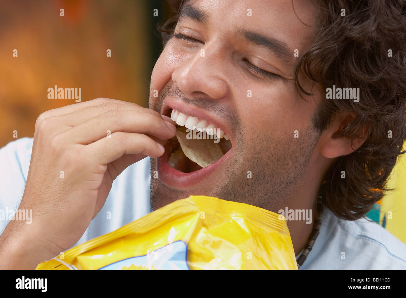 Close up Of A Young Man Eating Potato Chips Stock Photo Royalty Free close-up-of-a-young-man-eating-potato-chips-stock-photo-royalty-free