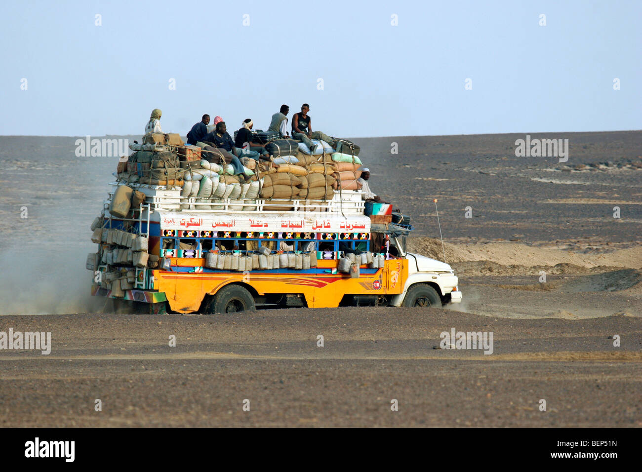 Heavily loaded bus with luggage and passengers on the roof driving