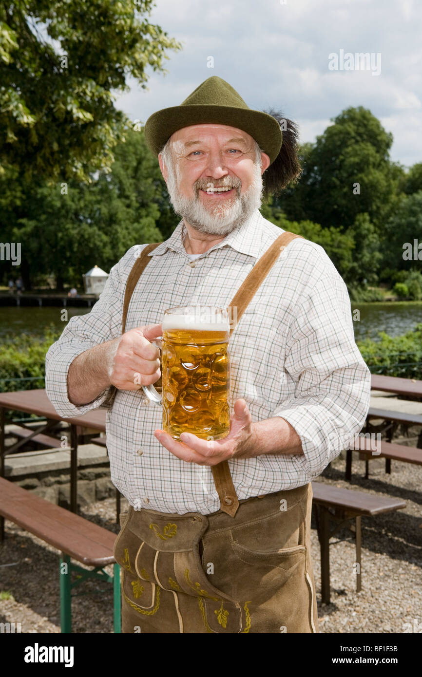 A traditionally clothed German man in a beer garden holding a beer