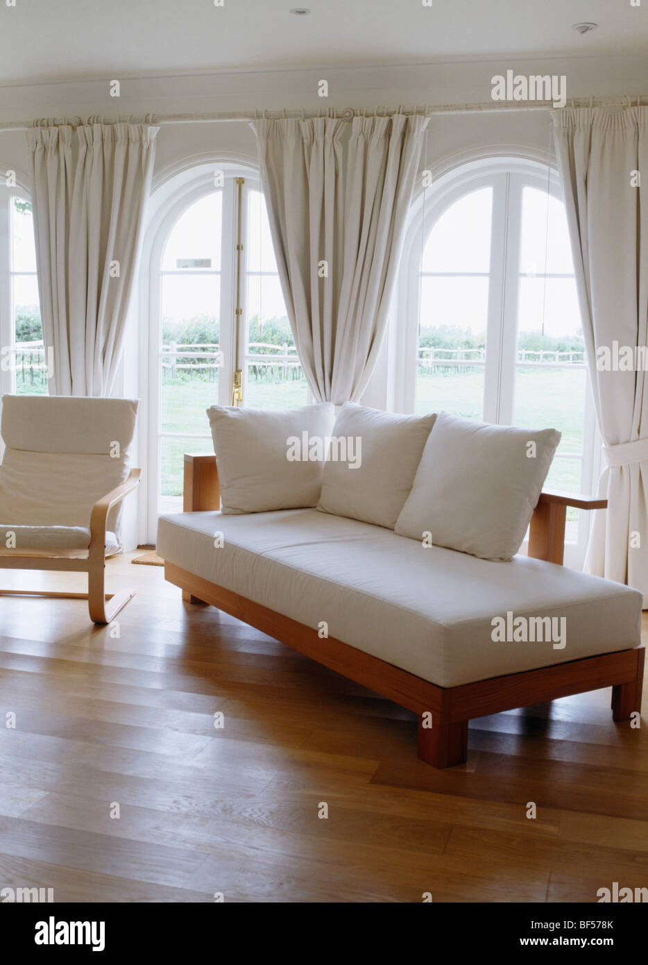 Day Bed With White Cushions In Living Room With Wooden Floor And