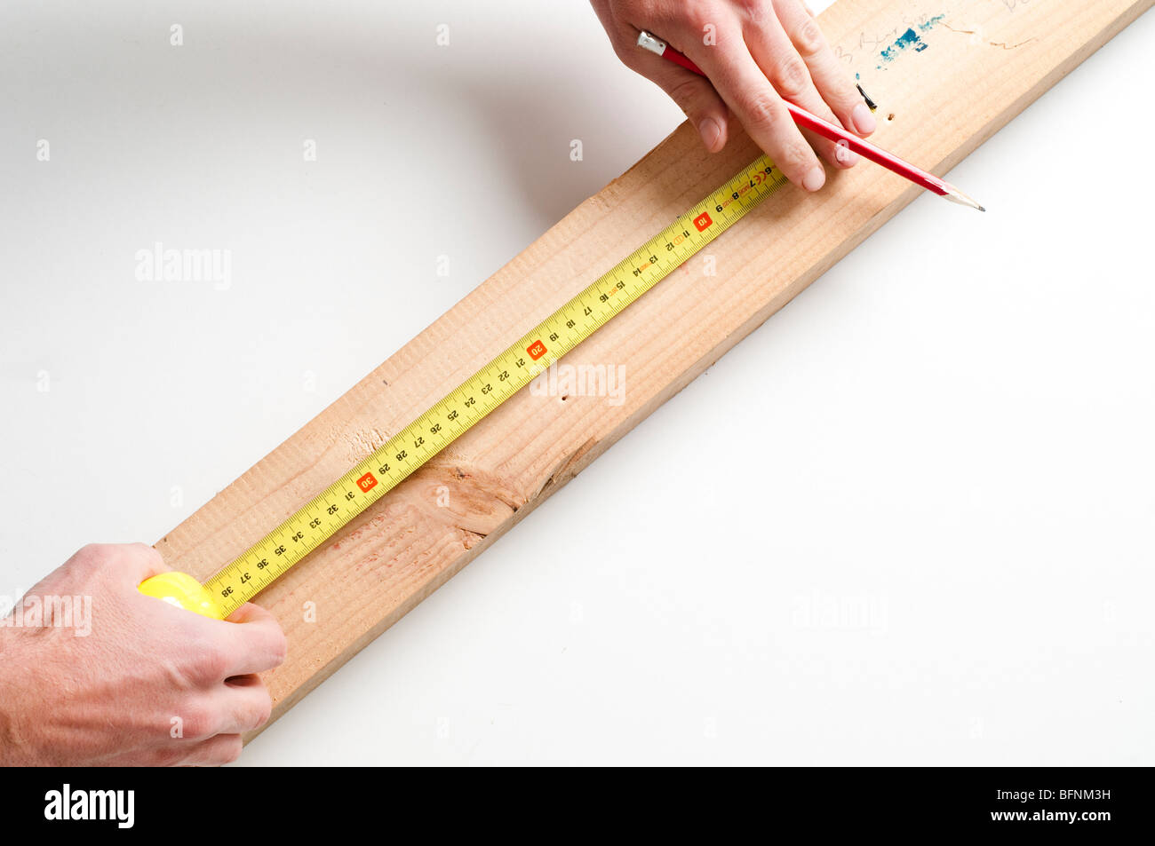 man measuring wood with tape measure and marking with pencil Stock