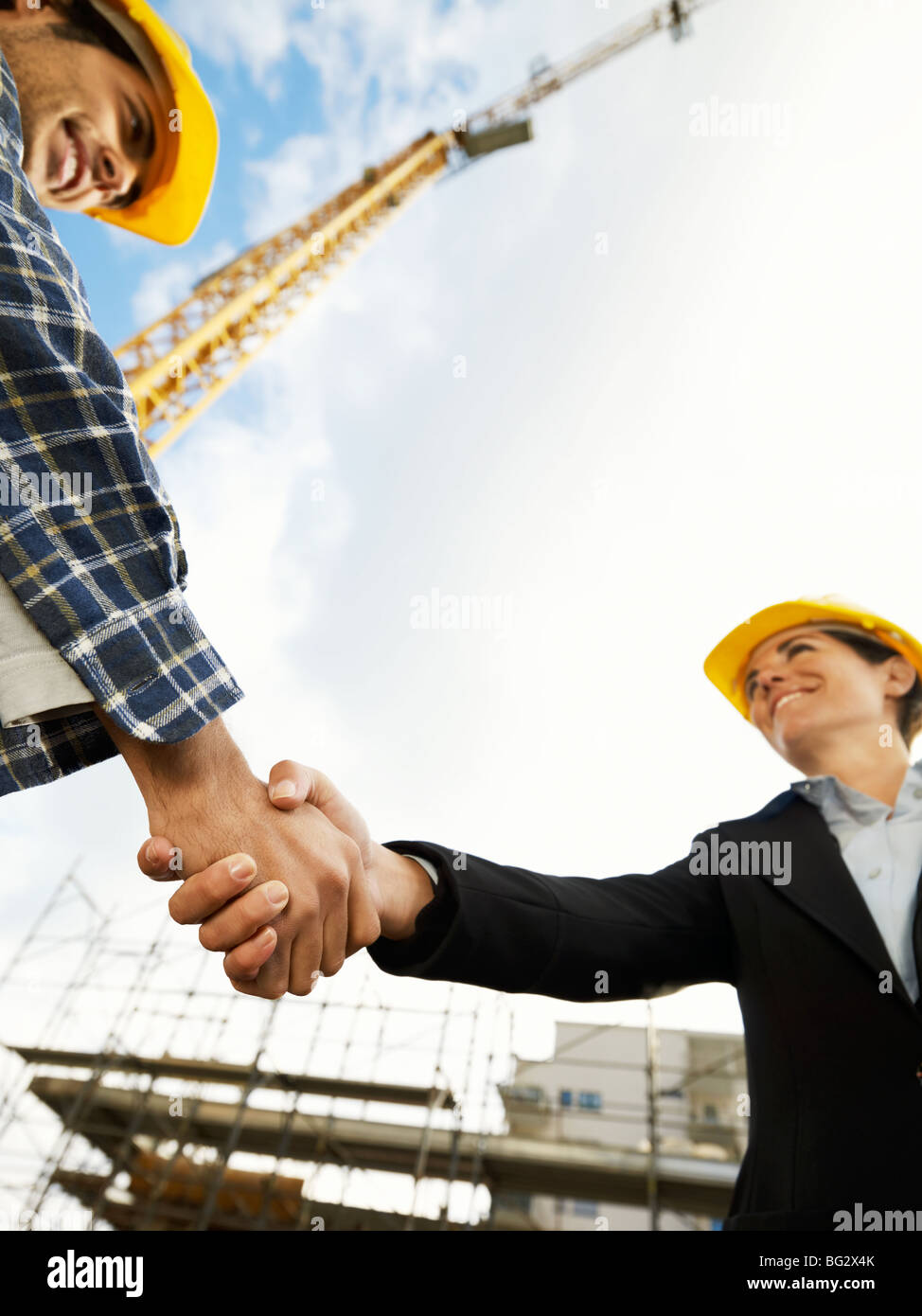 female architect and construction worker shaking hands. low angle female architect and construction worker shaking hands. low angle