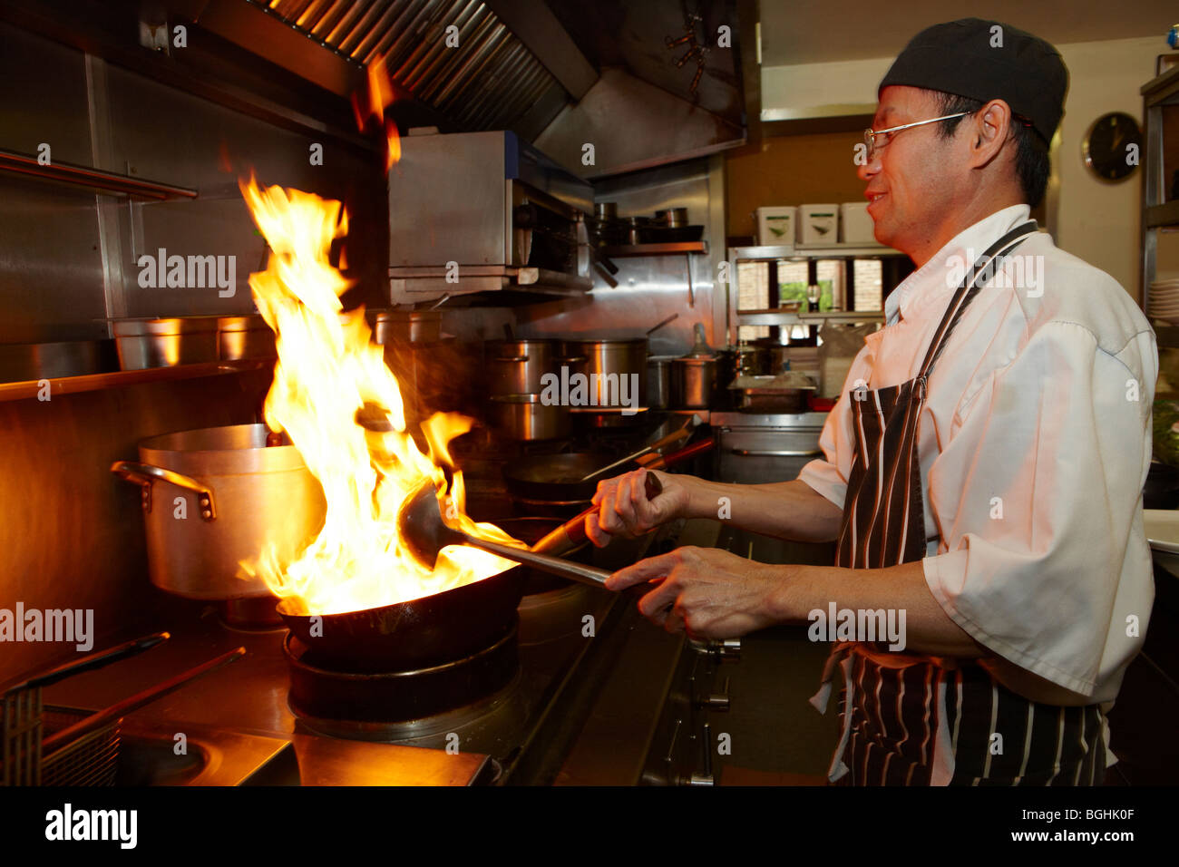 Restaurant Kitchen Chefs chef cooking in a kitchen with flames coming out of the frying pan Restaurant Kitchen Chefs chef cooking in a kitchen with flames coming out of the frying pan