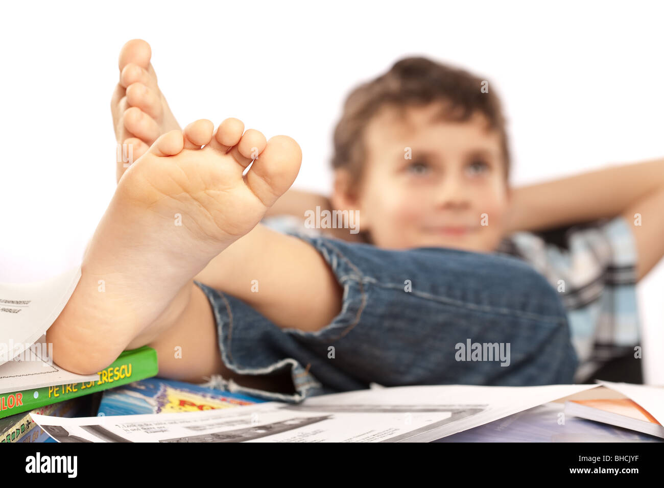 Portrait of a barefoot schoolboy with his feet up on his desk Stock