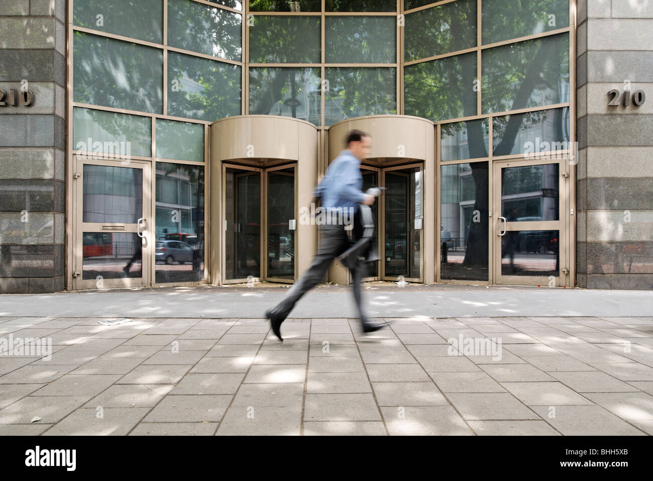 Motion blurred image of young business man walking quickly along Stock