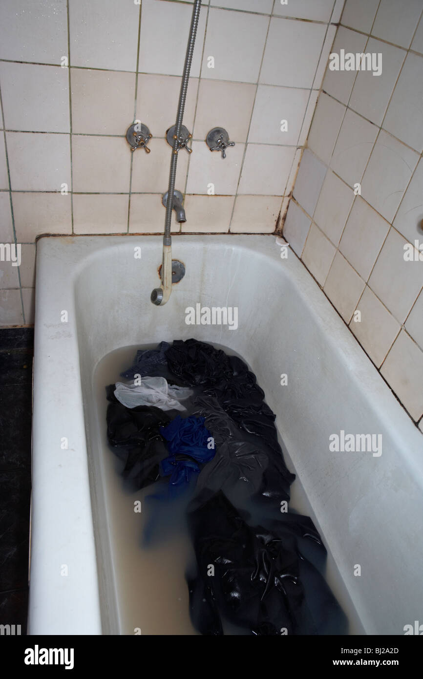 dirty washing in dirty water in a bath being washed in a run down Stock