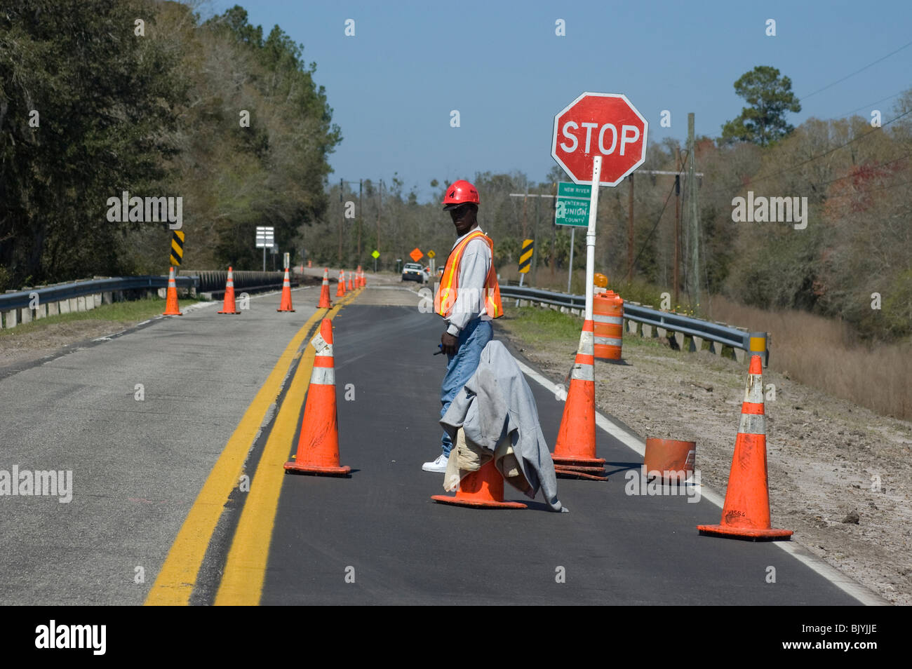 man working for highway road work crew tends the stop and caution Stock