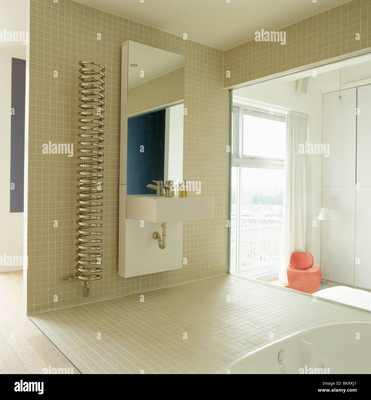 Chrome spiral radiator beside tall mirror and wallmounted basin in
