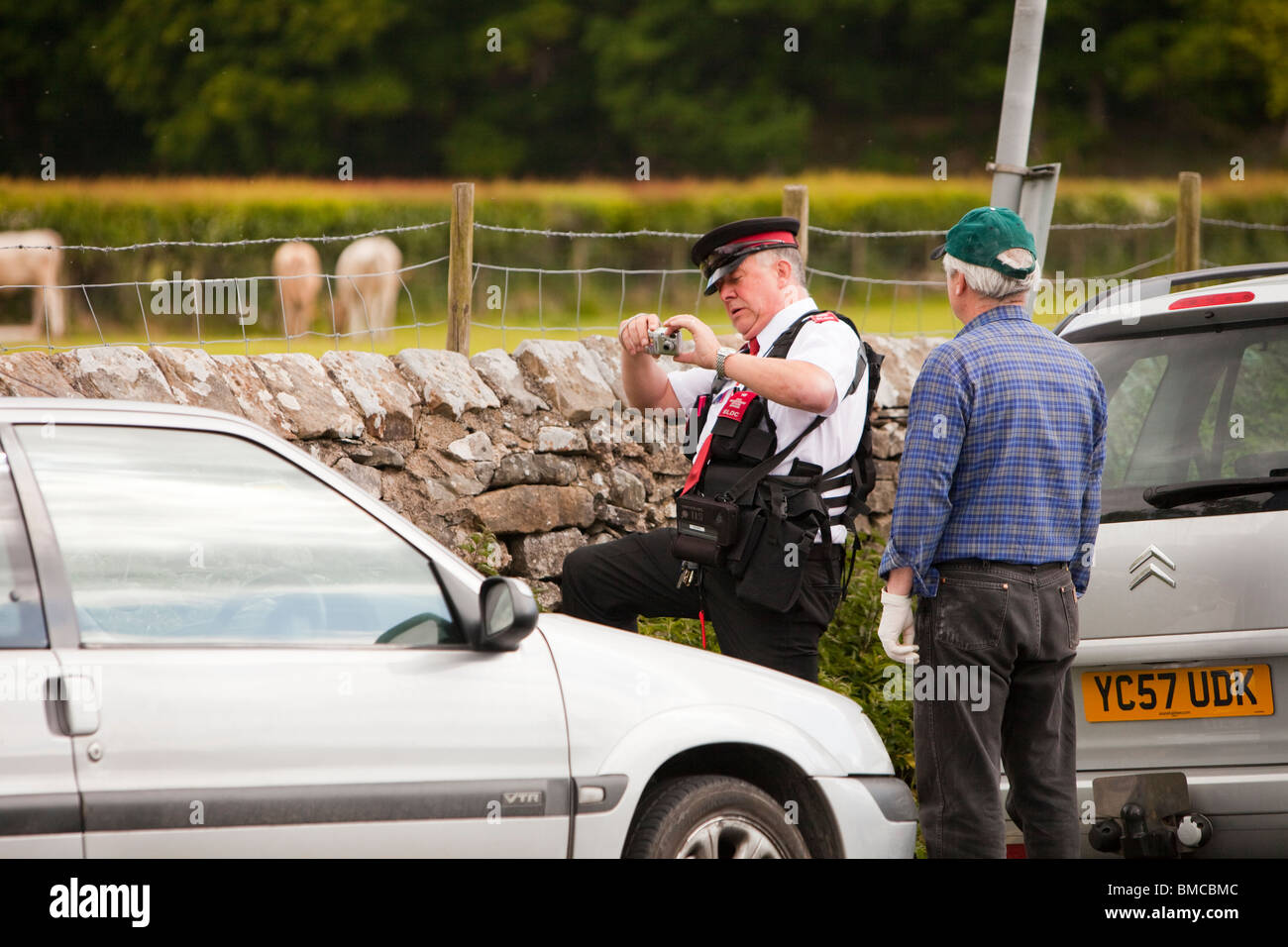A parking attendant issues a ticket to a car parked on double yellow