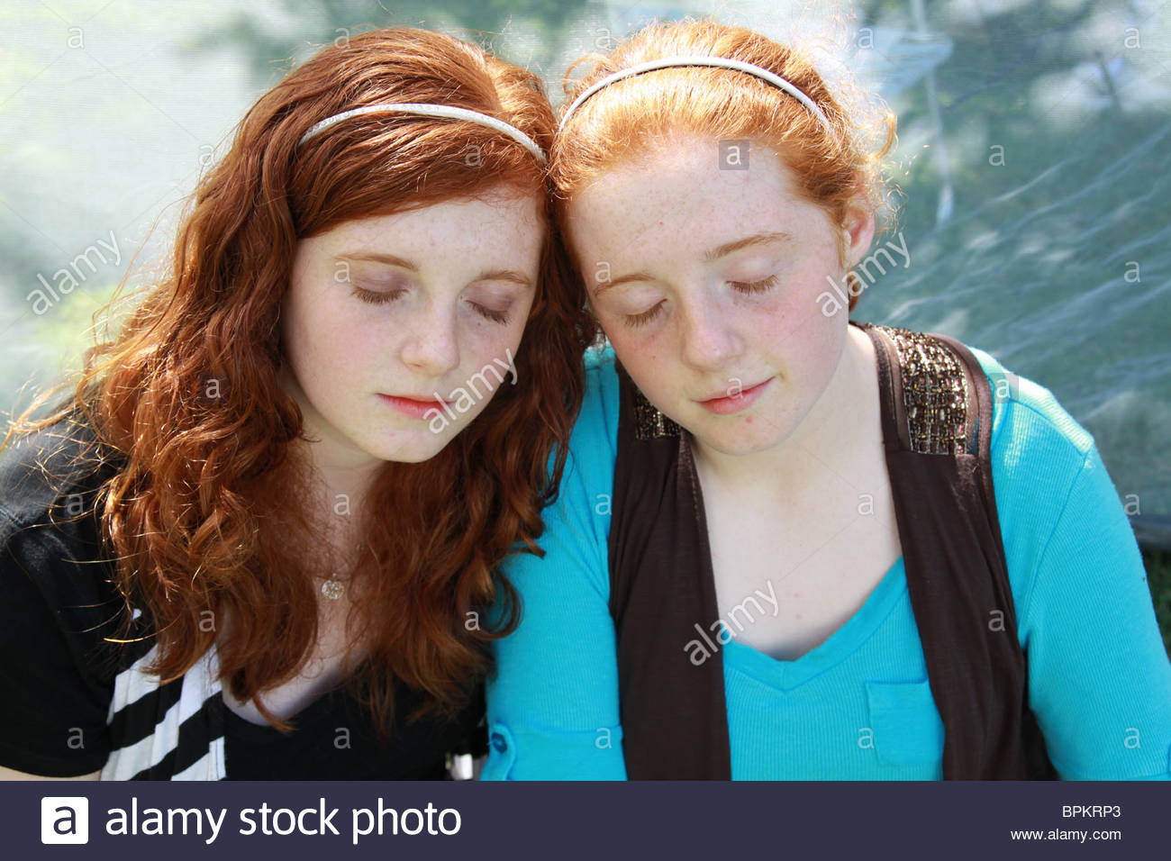 14 year old twin girls with red hair, with heads together and eyes