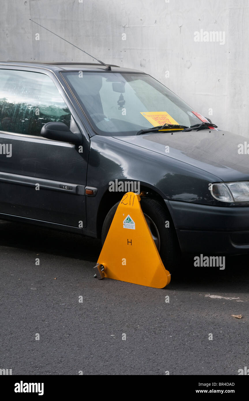 Illegal, untaxed and wheel clamped car in public street Stock Photo